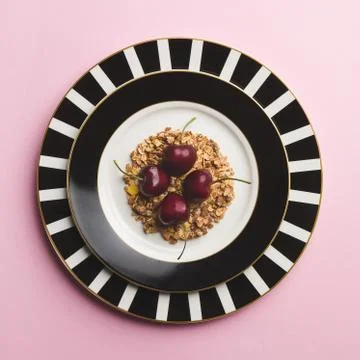 Top down view of four cherries in a bed of flakes, in black and white plates 写真素材