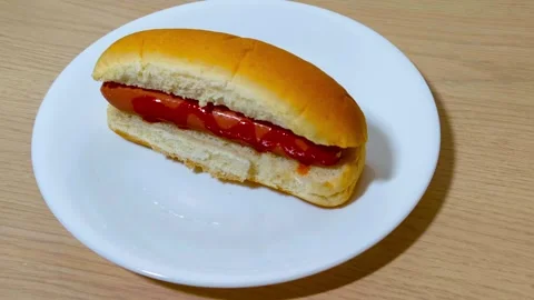 Top down view of fresh hot dog in a bun with sausage served on a white plat.. Stockbeeldmateriaal 318181888