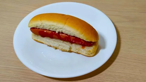 Top down view of fresh hot dog in a bun with sausage served on a white plat.. Stock Footage 318182301