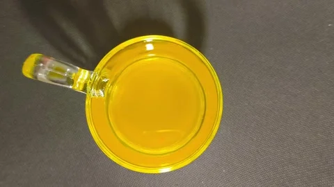 Top-down view of fresh orange juice in a clear handled glass cup on a black.. Video stock 318128048