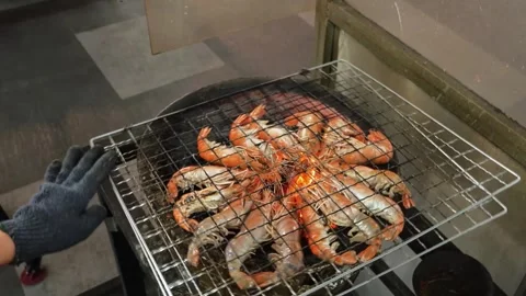 Top-down view of fresh prawns grilling over an open charcoal flame in a circular Stock Footage 344227768