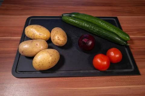 Top-down view of fresh raw vegetables arranged on a black cutting board on .. Stock Photos
