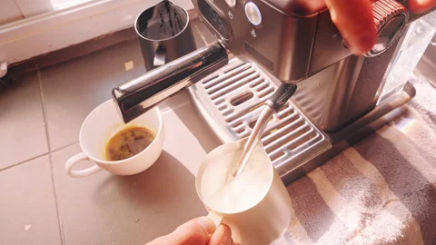 Top Down View Frothing Milk With Steam Wand In Metal Pitcher Beside Espresso Cup Stock Footage 331023999