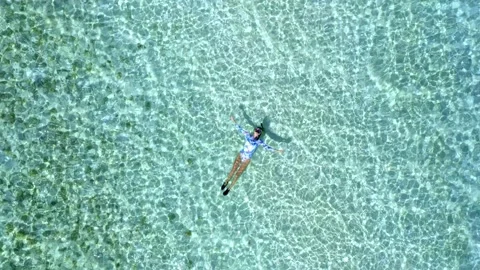 Top down view of a girl floating in a lagoon Stock Footage 163542205