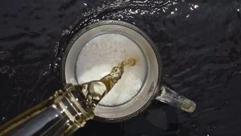 Top Down View of Golden Beer Pouring into Glass Mug on Wet Black Surface Stock Footage 335787880