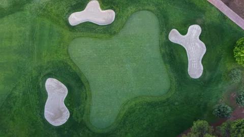 Top-down view of a golf course green surrounded by sand bunkers and lush Stock Footage 346640046