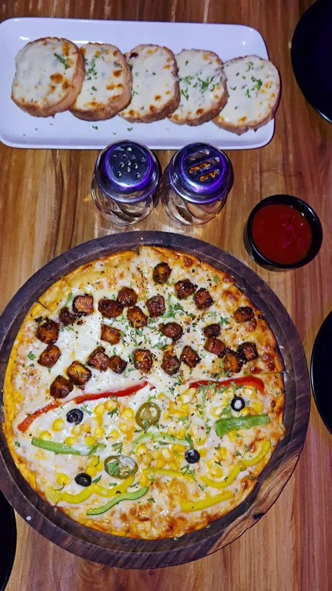 Top Down View of Gourmet Pizza With Garlic Bread and Dipping Sauce on Wooden Stockbeeldmateriaal 337562910