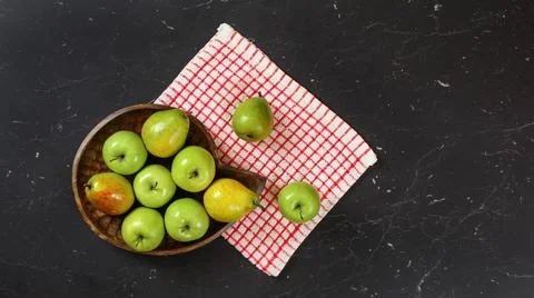 Top down view, green apples and pears in wooden carved bowl, red chequered ta Stock Photos