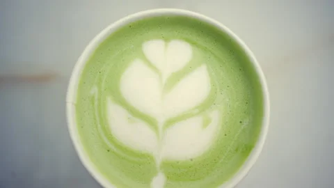 Top down view of a green matcha latte with detailed leaf shaped latte art made Stock Footage 335230496