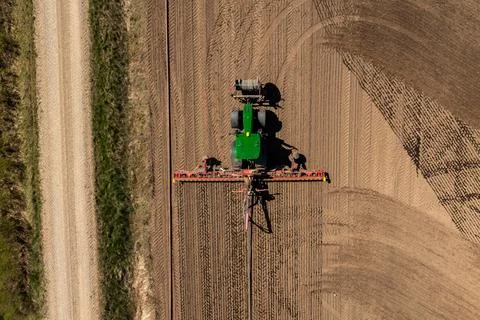 Top Down View of Green Tractor Tilling Field Near Dirt Road Stock Photos