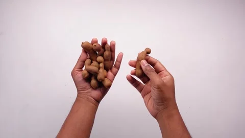 Top down view of a hand holding and picking up several pieces of tamarind f.. Stock Footage 332056703