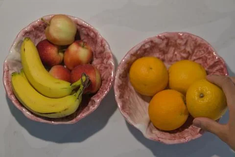 Top Down View of Hand Picking Up Orange from Fruit Bowl Stock Photos