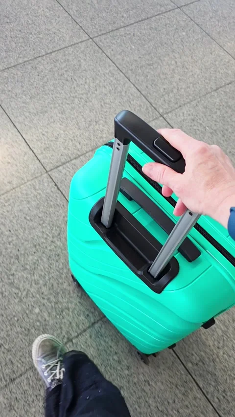 Top-down view of hand pulling teal hard-shell suitcase across airport termi.. Stock Footage 338133304