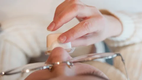 Top-down view of hand tilting open orange facial cream container toward relaxed Stock Footage 345652598