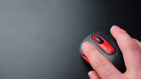 Top-down view of a hand using a black and red wireless mouse on a clean dark 스톡 동영상 329480053