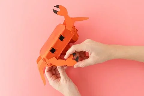 Top down view of hands crafting DIY crab toy made from orange painted egg c.. Stockfoto's