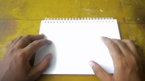 Top down view of hands flipping through the blank pages of a spiral bound n.. Stock Footage 332913687