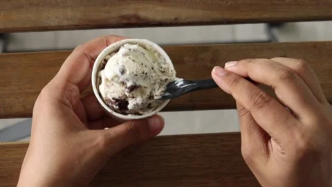Top-down view of hands holding and eating delicious oreo ice cream with a b.. Stockbeeldmateriaal 333260278