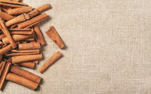 Top down view - Heap of cinnamon bark sticks on linen tablecloth, space for t Stock Photos