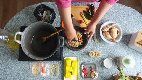 Top-down view of Home cook slicing fresh turmeric and grinding herbs with Stock-Footage 344910716