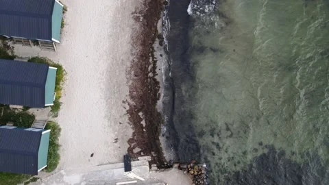 Top down view of huts and waves breaking against the beach Stock Footage 147543272