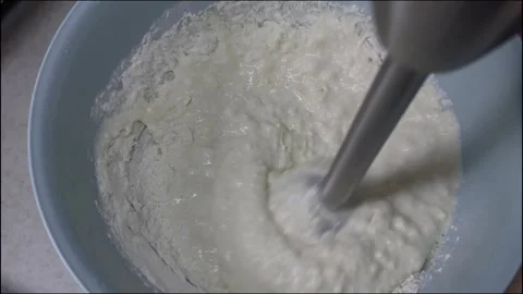 Top-down view of an immersion blender mixing white flour and liquid Vídeos de archivo 335046134