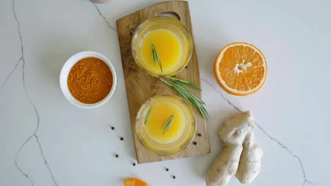 Top down view of immune boosting orange turmeric ginger shots on marble Stock Footage 335956201