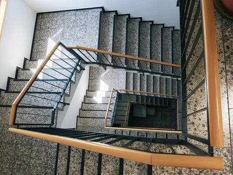 Top down view of indoor terrazzo staircase with black metal balustrades and.. Stock Photos