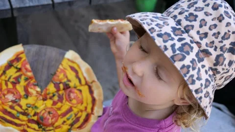 Top down view to kid gourmet eating piece of pizza. Cinematic video of blond Stock Footage 253356550