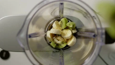 Top down view kiwi chunks are thrown into blender to make smoothie. vegan drink Stock Footage 170628588