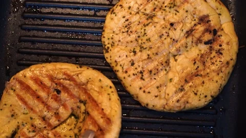 Top down view of kulche flat bread cooking over a ribbed black pan and searing Video stock 130595464