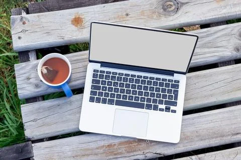 Top down view of a laptop mockup and a cup of tea on a rustic wooden deck 库存照片