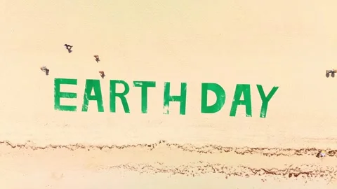 Top down view of large green title on tropical beach says EARTH DAY. People 스톡 동영상 273869548