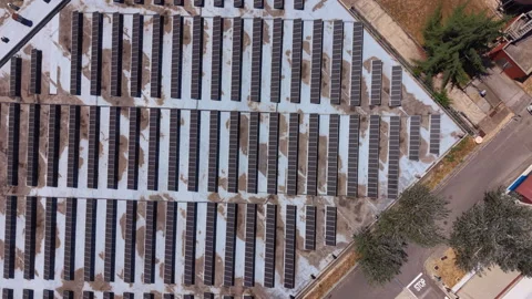 Top-down view of large solar panel array on flat rooftop with snow patches 库存影片 343888007