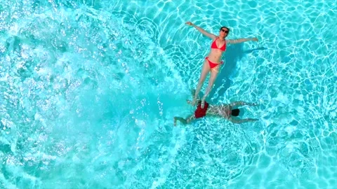 Top down view as a man dives into the pool while woman is laying on her back Video stock 342958091