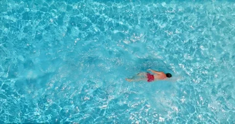 Top down view of a man in red shorts swims in the pool. Slow motion Stock-Footage 252613803