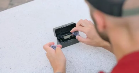 Top-down view of a man setting up a compact wireless microphone kit in its Video stock 328533924