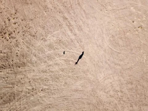 Top down view of a man walking his dog in a dirt field Stock Photos