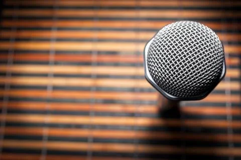 Top-Down View of A Microphone Head and Silver Grille on A Striped Yellow and Stock Photos