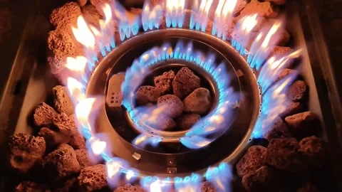 Top down view of a modern gas burner with lava rocks creating vibrant blue and Stock Footage 347030052