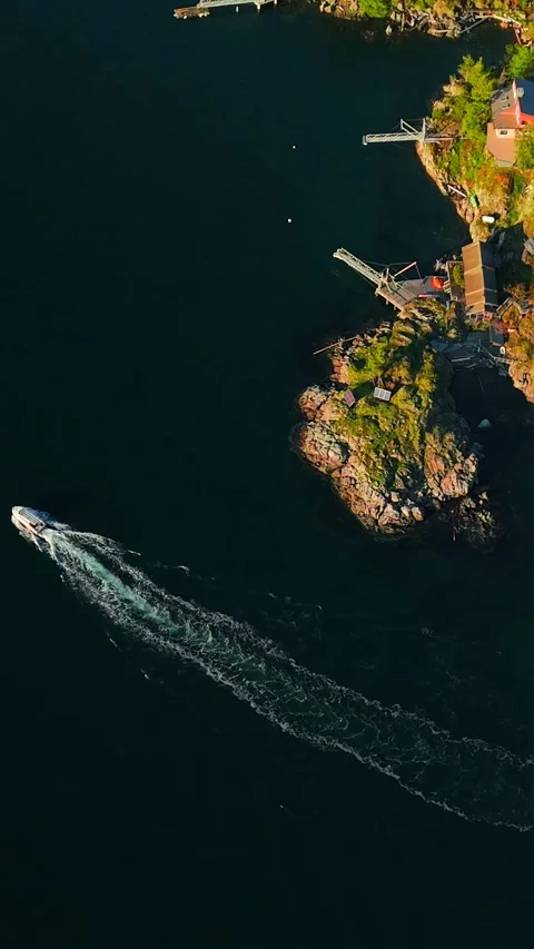 Top down view of motor boat sails around the coast of the island. Camera rotates Stock Footage 322535788