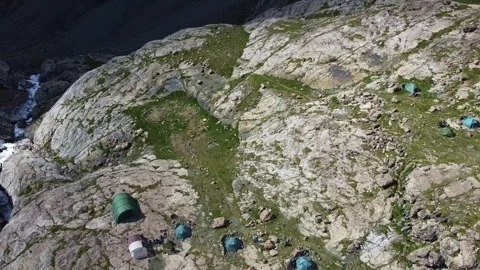 Top down view of mountain campsite with tents on rocky cliff near waterfall 库存影片 334326559