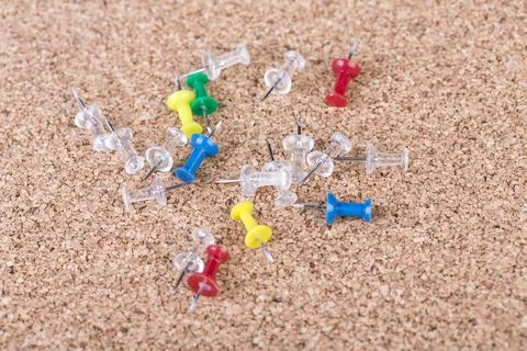 Top down view multicolored thumb tacks lying on a cork board Stock Photos