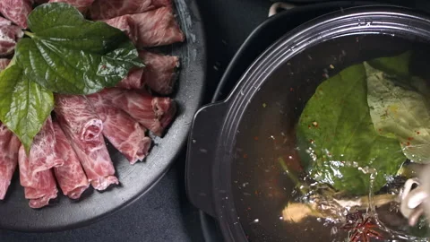 Top down view of mushrooms falling into Asian hotpot water Stock Footage 157842893