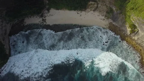 Top down view of an ocean cliff covered in greenery. White foam with turquoise Video stock 224755724