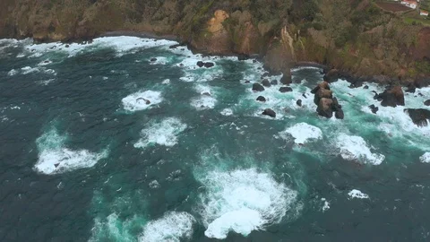 Top down view of ocean waves hitting coastal rocks and making white foam. Aerial Stock Footage 121269872