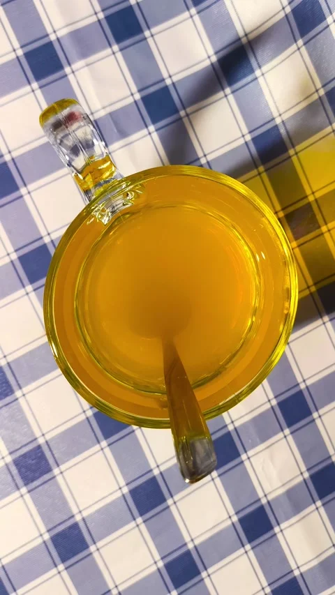 Top down view of orange juice in a clear glass with spoon on  checkered pic.. Stockbeeldmateriaal 318126280