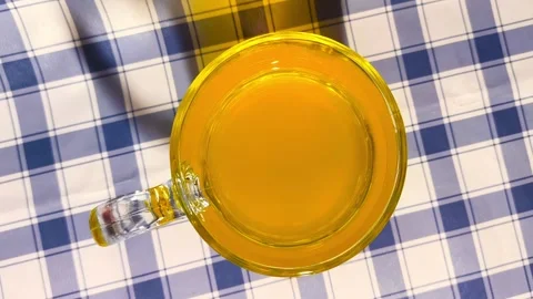 Top down view of orange juice in a clear glass on checkered picnic tableclo.. 動画素材 318126675
