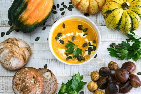 Top down view of organic pumpkin soup in a white bowl framed by chestnuts Stock Photos