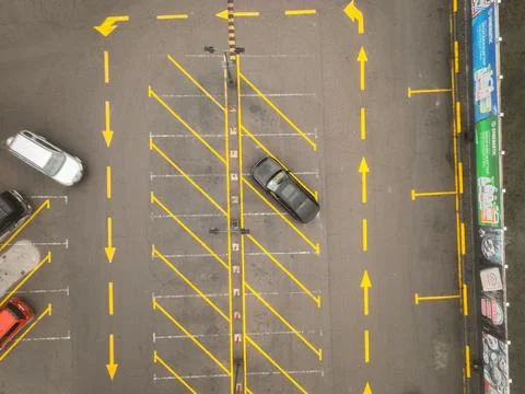 Top-down view of parking lot with yellow arrows and cars Stock Photos